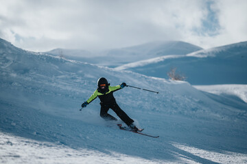 Wall Mural - A skier is captured mid-action, losing balance while skiing down a snowy mountain slope surrounded by serene winter landscapes.