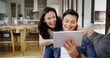 © peopleimages.com - Home, couch and couple with tablet for laughing, streaming service and watch movie for entertainment. House, man and woman with digital for website subscription, video opinion and bonding with joke