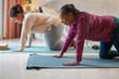 © Sabrina - Mature african mother and daughter doing yoga exercise together at home - Healthy lifestyle and family love concept - Focus on senior woman hand