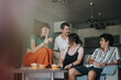 © qunica.com - A joyful gathering of young friends enjoying coffee in a cozy living room. They are laughing and sharing happy moments, creating a warm and friendly atmosphere.