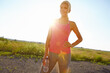 © peopleimages.com - Break, runner and woman with smile, blue sky and happy for wellness with exercise, training or healthy. Outdoor, athlete and jogger with sportswear for workout, space or person in nature for practice