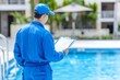 © Sebelas Studio - Pool technician inspecting documents near a residential pool