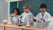 © Summit Art Creations - Children doing experiment in science lesson while standing at blackboard at laboratory. Happy student discovering and learning about biochemical liquid while inspecting and mixing sample. Pedagogy.