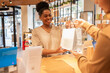 © ADDICTIVE STOCK - Smiling assistant handing a bag in a cosmetics store setting