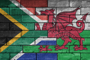 Wall Mural - colourful painted big flag of south africa and flag of wales on a massive old brick wall background. concept