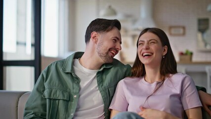 Wall Mural - Laughing couple looking film on TV at sofa closeup. Pair enjoy amusing program