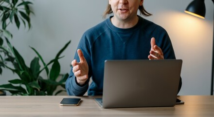 Canvas Print - A man is sitting at a desk with a laptop and a cell phone