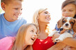 © peopleimages.com - Mother, children and excited outdoor with dog, new family pet and pleased for adoption approval. Woman, happy kids or puppy in backyard for bonding, fun or responsibility on summer holiday with laugh