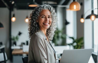 Wall Mural - Woman in a modern office smiling while using a laptop 