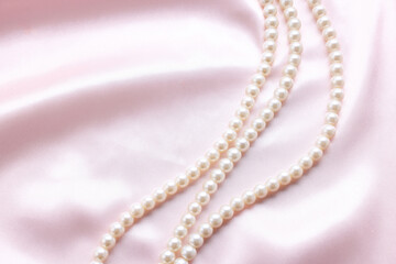 Wall Mural - Elegant pearl necklace on pink fabric, top view. Space for text