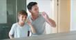 © peopleimages.com - Mirror, dental health and father brushing teeth with child in bathroom for preventing gum disease. Bonding, oral care and dad teaching boy kid mouth routine in morning for fresh breath in home.