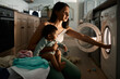 © Nina Lawrenson/peopleimages.com - Home, baby and mom with machine for laundry, multitask late and stress for household chores. House, girl and single mother with burnout for washing clothes, child care and responsibility at night