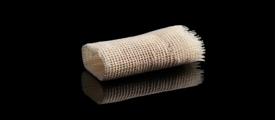 Aufkleber - Textured cylindrical object with a woven appearance on a reflective black surface with copy space for text.