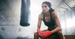 © peopleimages.com - Fitness, boxer and tired woman on break in gym for intense workout, fatigue and exercise recovery. Boxing, resting and athlete relax in sports club for thinking, sweating or breathing for body health