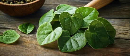 Wall Mural - Fresh green betel leaves arranged on a wooden surface with a bowl of spices in the background Copy Space