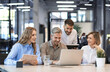 © ty - Four business professionals using laptop on desk discussing strategy company