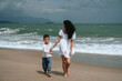 © alexkoral - Happy mom and son walking along the beach by the sea on summer vacation