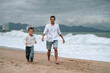 © alexkoral - happy dad with a child son are walking along the beach by the sea on a summer vacation