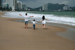 © alexkoral - back of happy family with a child boy son running along the beach by the sea in summer