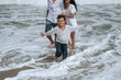 © alexkoral - happy child boy son with his family running along the beach by the sea in summer on vacation