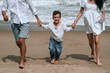 © alexkoral - happy child boy son with his parents running along the beach by the sea in summer on vacation