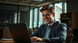 © adynue - Smiling businessman working on laptop in modern office space. Young student using computer remote studying, watching online webinar, zoom virtual training on video call meeting