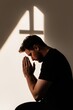 © Anna - Young man praying silently in church with cross shadow on wall