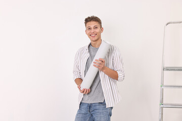 Wall Mural - Smiling handyman with roll of wallpaper indoors