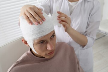 Wall Mural - Doctor bandaging patient's head in clinic, closeup