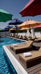 Poster - A serene poolside scene at a tropical resort, featuring neatly rolled white towels placed on plush lounge chairs under tall palm trees.