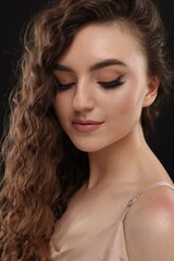 Canvas Print - Beautiful young woman with long curly brown hair on black background, closeup