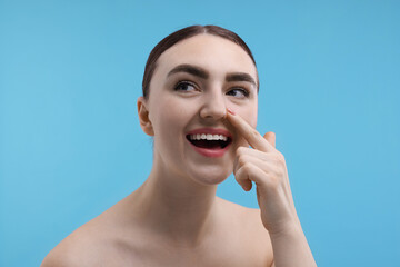 Wall Mural - Woman touching her nose on light blue background