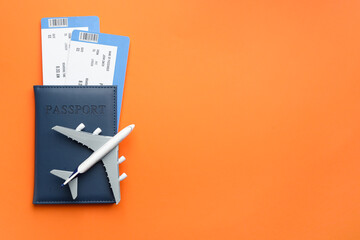 Wall Mural - Travel agency. Flight tickets, passport and plane model on orange background, top view. Space for text