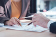 © Nittaya - Business Partners Reviewing Documents: Close-up shot of two business partners, a man and a woman, attentively reviewing financial documents, deeply engaged in a collaborative discussion. 