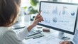 © olga_demina - Businesswoman pointing at computer screen showing financial data charts and graphs, analyzing market trends and investment opportunities in modern office workspace