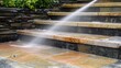 © Sawyer0 - A professional cleaning service uses a high-pressure water jet to thoroughly wash exterior stone stairs, removing dirt and grime for a spotless finish.