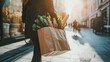 © cactusimage - Woman walking with a grocery bag in an urban street setting