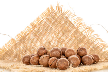 Wall Mural - Several macadamia nuts on a  jute napkin, close-up, isolated on a white background.