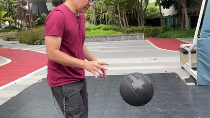 Wall Mural - A senior East Asian man is practicing and playing basketball alone in a public park.