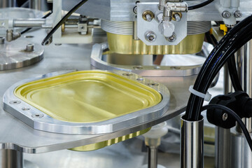 Poster - A machine is making a can of food. The can is yellow and silver. The machine is very precise and efficient