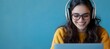 © DesignINKZ - Smiling young woman with glasses and headphones engaged in distance learning on laptop.