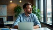 © miss irine - Man sits at desk in office. Looks thoughtful working on laptop. Quiet, focused environment. Possible virtual team meeting. Office tech use. Businessman working. Collaboration key. Modern workplace
