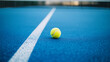 © MicroTee - A tennis ball resting on a blue court with a white line running through it