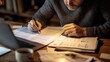 © Topuria Design - Focused mature professional reviewing documents and filling paperwork at his home office desk, working late with laptop and coffee cup near