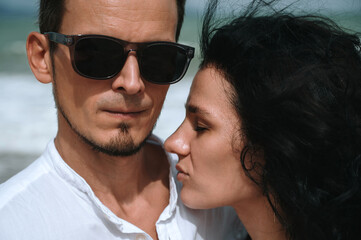 Stylish young beautiful couple in love hugging on the beach by the sea in summer on vacation