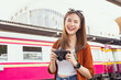 © sitthiphong - Young Asian woman traveler wearing orange shirt with taking picture using a camera at railway station. summer tourism concept.