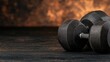 © angel_nt - pair of heavy dumbbells rests on a textured surface in a dimly lit space, emphasizing the focus on strength training and fitness goals in a gym-like atmosphere