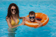 © alexkoral - happy young mother teaches child boy son to swim in swimming pool at a hotel on vacation at a resort in the summer