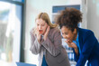 © Phushutter - Two young women, an African American and a Russian, both wearing formal suits, collaborate in a modern business office, consulting financial charts,  engaging in professional discussions.