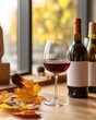 © Somporn - A cozy autumn scene featuring a glass of red wine, a few wine bottles, and colorful fall leaves on a wooden table with sunlight filtering through a window.